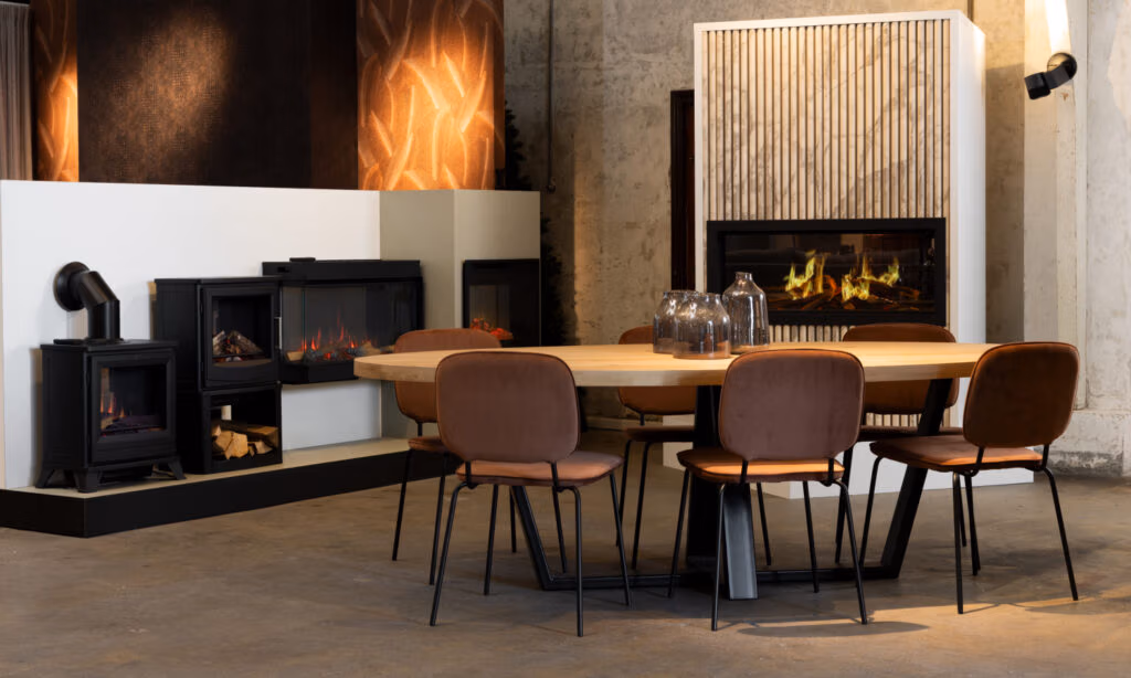 Een moderne eethoek met een lichte houten tafel, zes bruine gestoffeerde stoelen, glazen vazen als middelpunt, betonnen muren en twee open haarden - een zwarte vrijstaande met stijlvolle haardaccessoires en een ingebouwd in een wand met houten panelen.